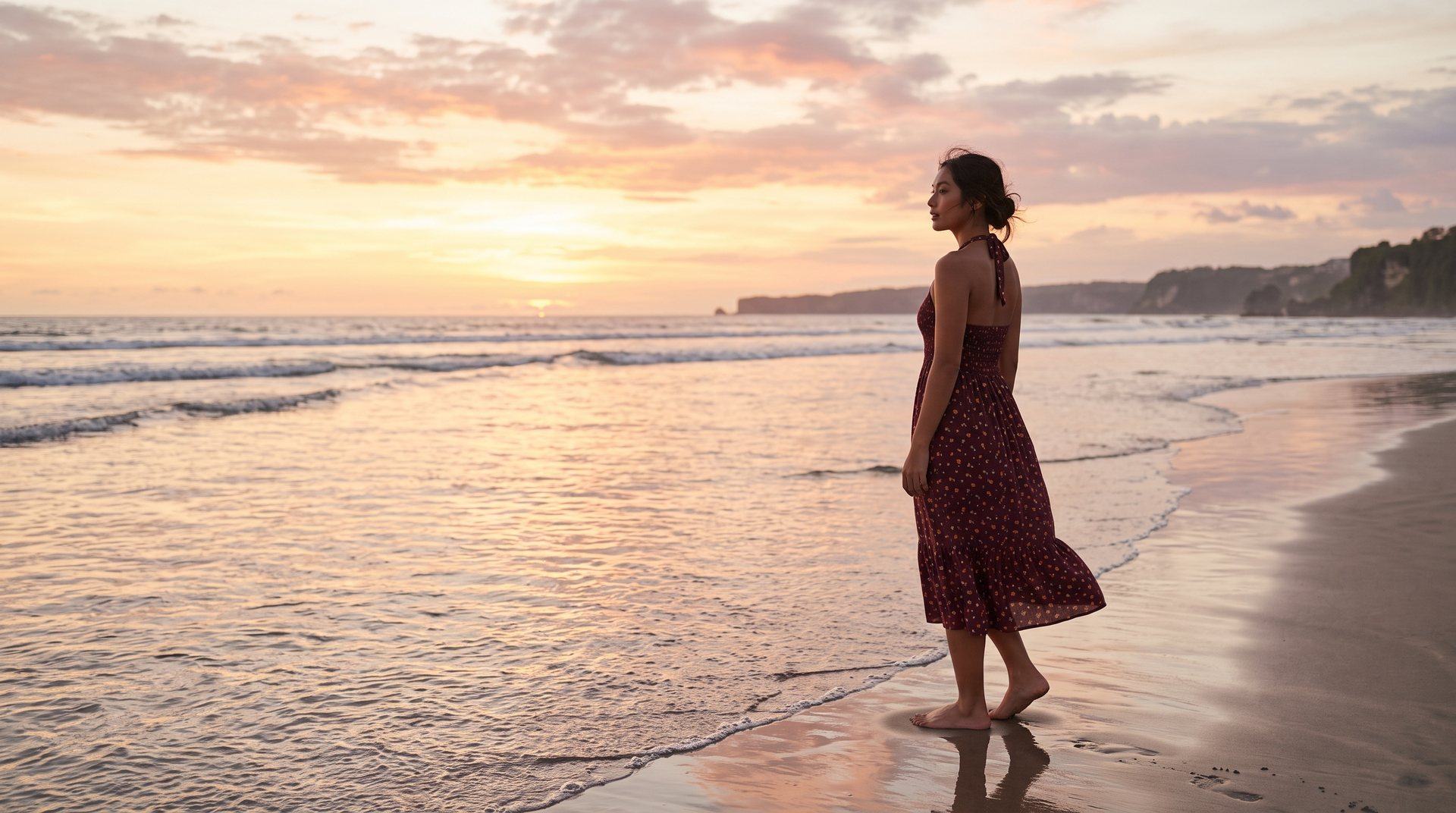 Perempuan memakai Sekar Halter Dress merah marun di pantai Bali saat matahari terbenam